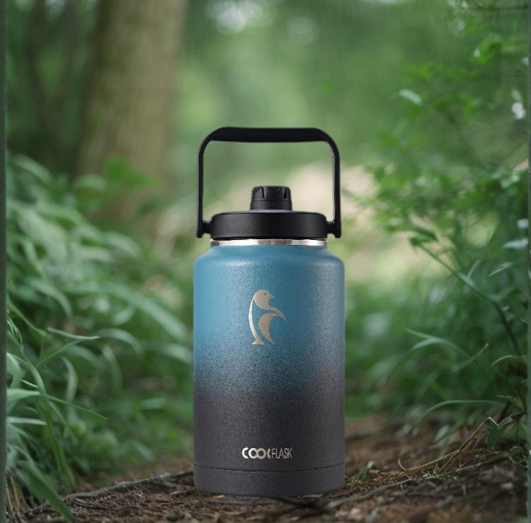 Blue insulated bottle with black lid in a forest setting